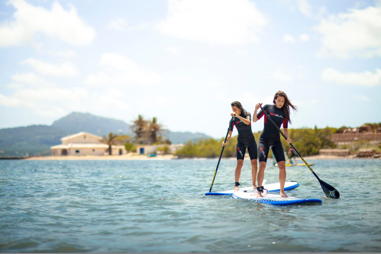 2 chichas haciendo paddle surf en Fornells